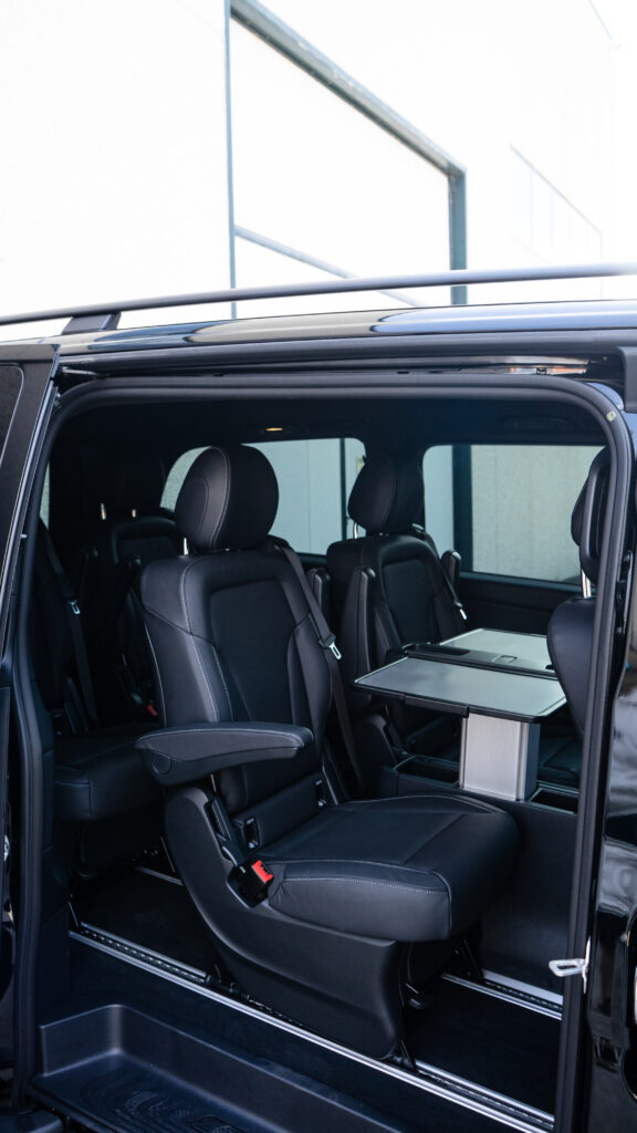 El versátil interior trasero de una Mercedes Clase V de RiojaBlack, equipado con asientos de cuero y una mesa plegable para negocios u ocio.