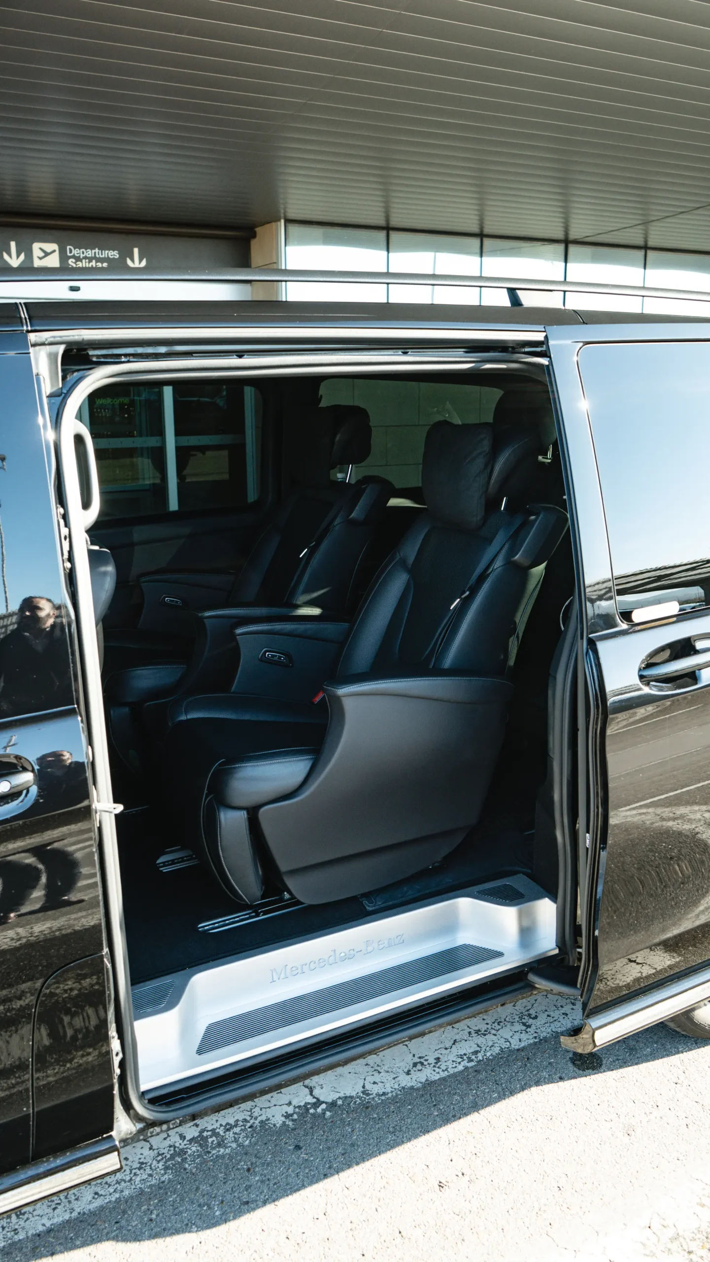 A black Mercedes-Benz V-Class from the RiojaBlack fleet, parked at a scenic La Rioja winery with vineyards in the background, ready for a private wine tour.