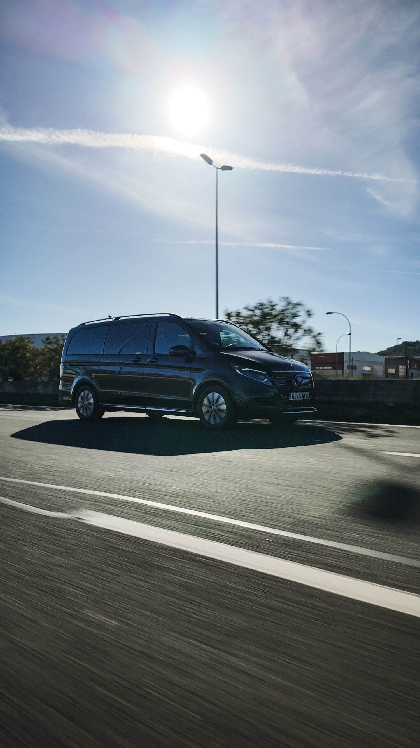 Black Mercedes-Benz EQV electric van driving on a scenic road, providing VIP support and luggage transfers for the Camino de Santiago - RiojaBlack.