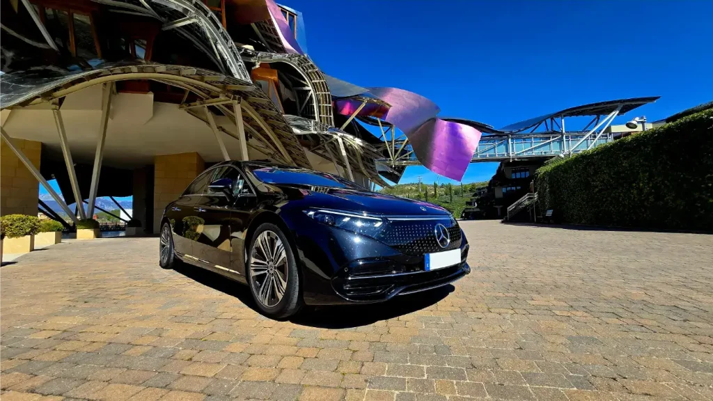 A one-of-a-kind Mercedes EQS electric vehicle from the private chauffeur fleet parked in front of the spectacular, cutting-edge building of the Marqués de Riscal winery in La Rioja Alavesa.